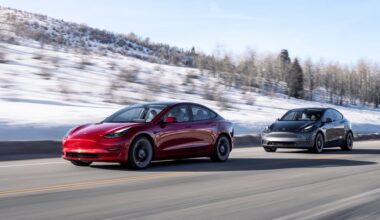 Two Tesla cars driving down the road.