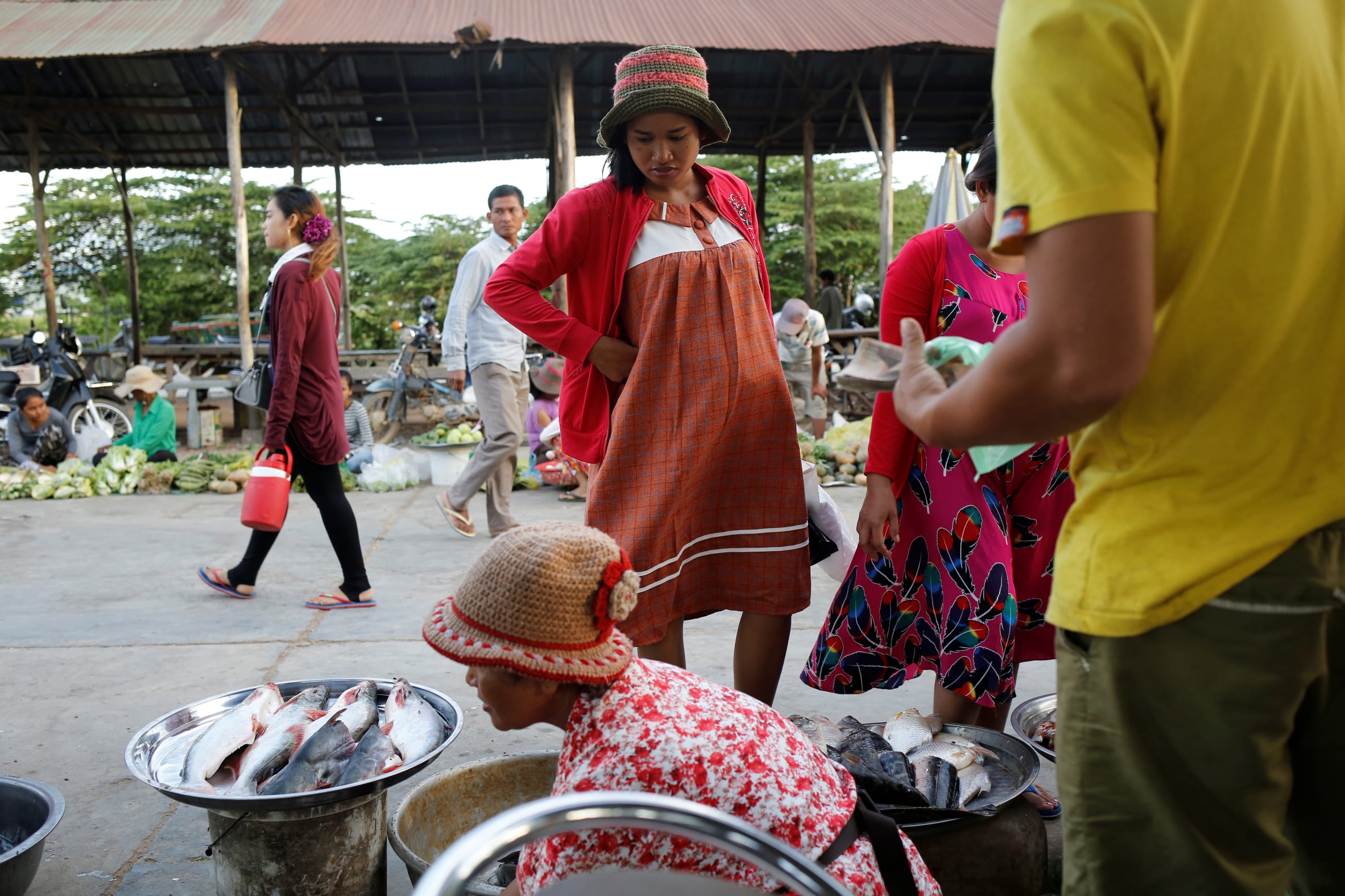 Khen Srey Touch, 27, who is nine months pregnant, buys food at a market outside, in Kampong Speu, Cambodia, on July 4, 2018.