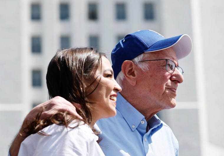 Sen. Bernie Sanders, I-Vt., and Rep. Alexandria Ocasio-Cortez, D-N.Y., look toward the crowd 