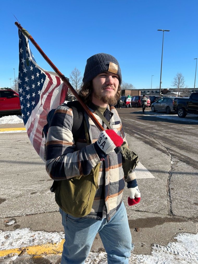 Niklas Lindstrom stands outside holding an American flag attached to a pole