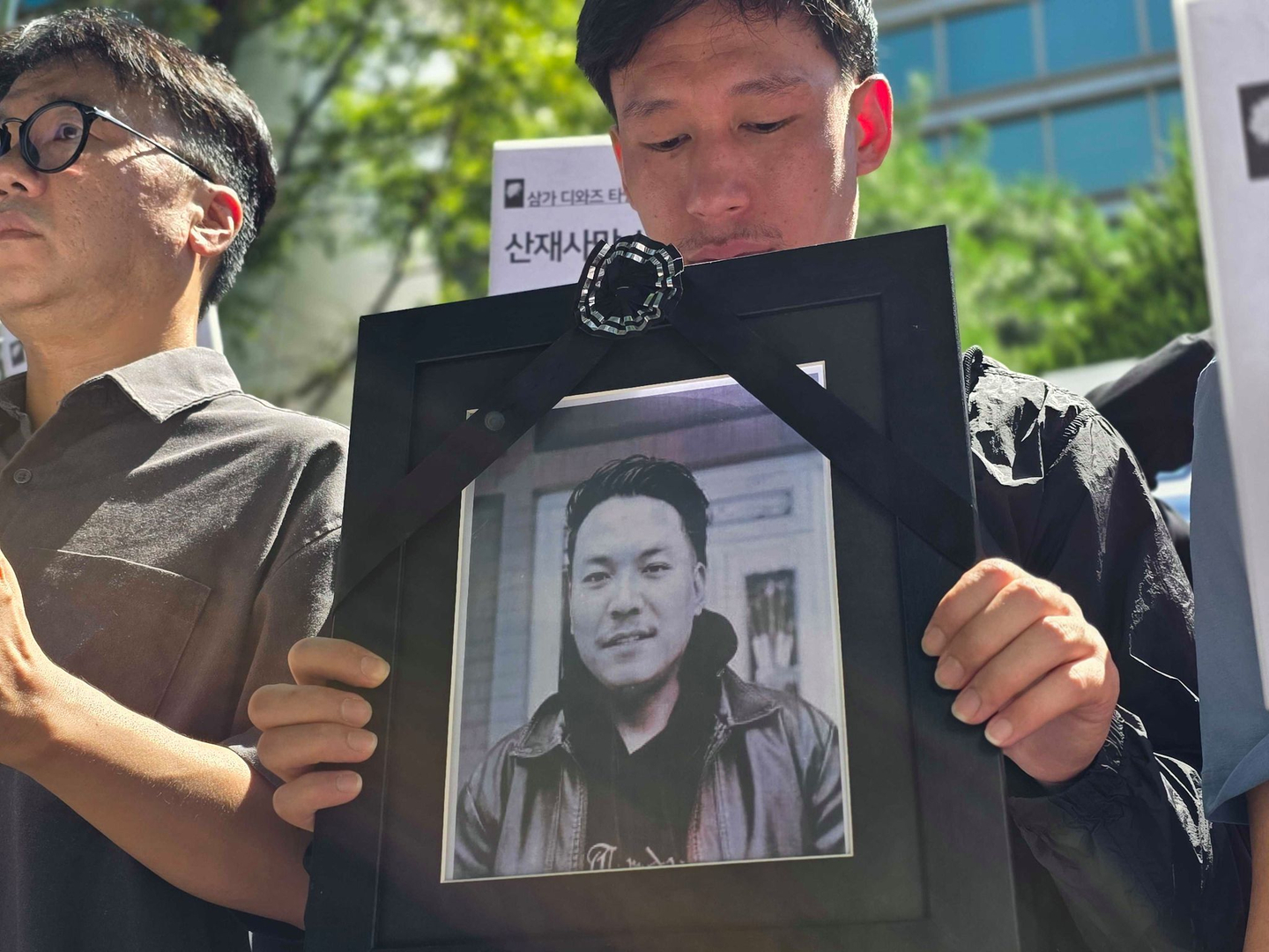 A coworker of Diaz Tamang, who dies in an industrial accident at a factory in Hwaseong, Gyeonggi in August 2025, holds Tamang’s portrait at a press conference. [LEE YOUNG-KEUN]
