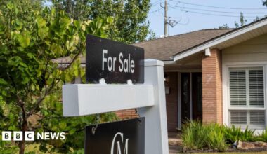 A for sale sign is seen in front of a house.