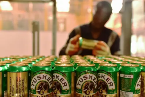 AFP via Getty Images An employee of the East African Breweries Limited sorts Tusker beer cans in 2019 at the company's plant in Ruaraka, Kenya.