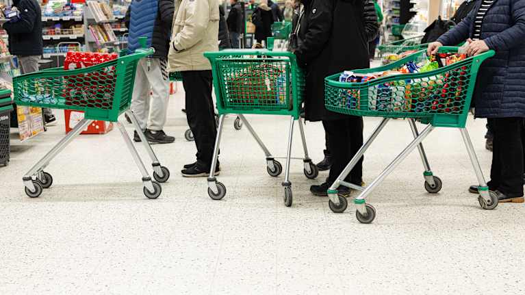 Customers with full shopping carts standing in line at a store.