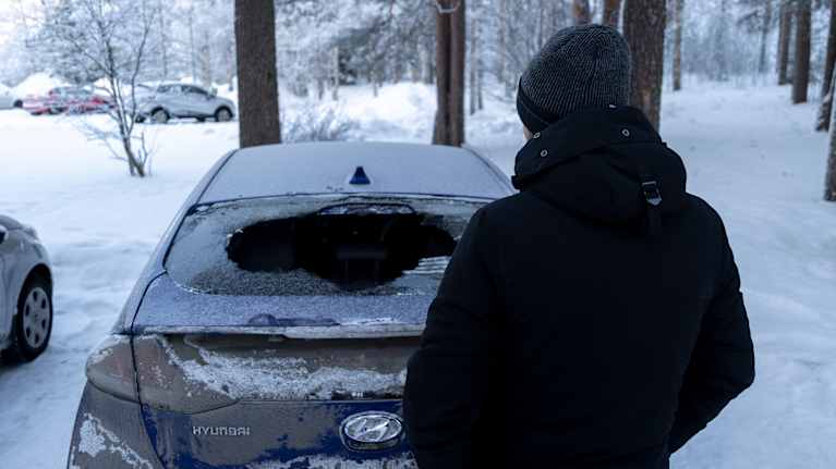 Taksinkuljettaja katsoo taksiaan, josta on rikottu tuulilasi.