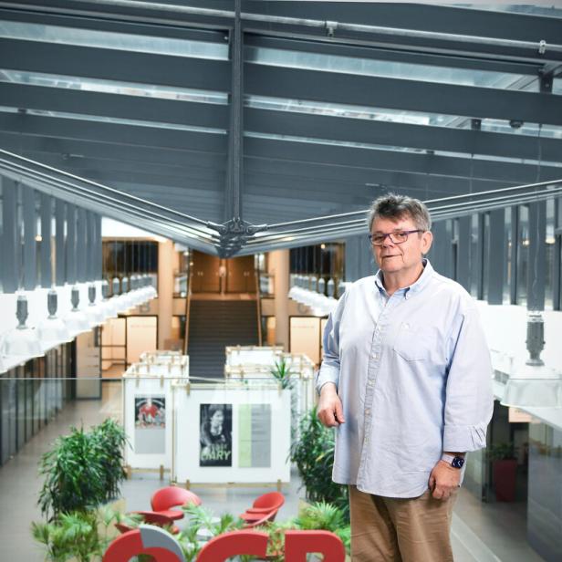 Ein Mann steht vor dem OGB-Logo in einem modernen Gebäude.