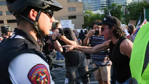 Reuters A man points and shouts at a line of armed police during a protest in Austin, Texas, on 10 June 2025
