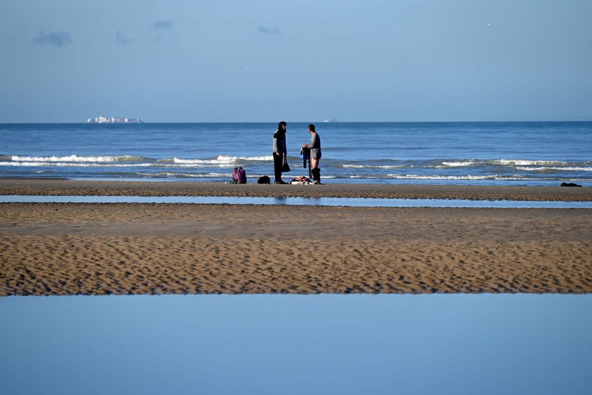 Migrants take off clothes after being rescued following their unsuccessful attempt to cross the Channel in a inflatable boat on a beach in Sangatte, northwestern France on December 13, 2025. (AFP via Getty Images)