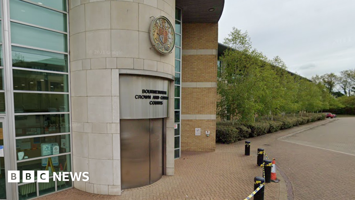Google Street View of the front of Bournemouth Crown Court. The revolving doors are closed and a sign in black writing above the door says Bournemouth Crown and County Courts. Above the sign on the round entranceway is a round crest with a central badge flanked by a lion and a horse.