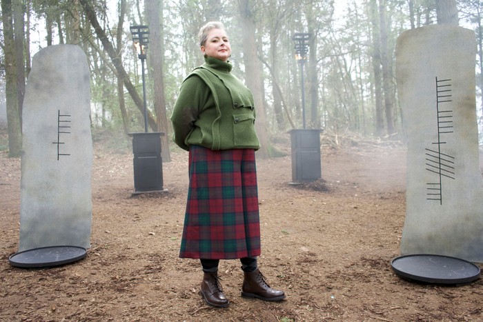 Siobhán McSweeney stood in the middle of a woodland with her arms behind her back.