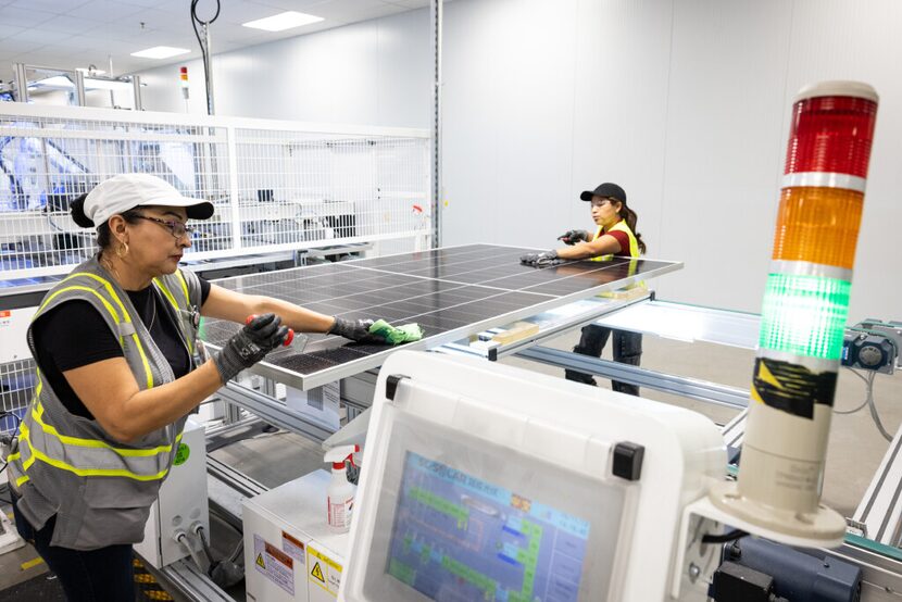 Production employees Raquel Sanchez Nino, left, and Kenia Landaverde check solar panels for...