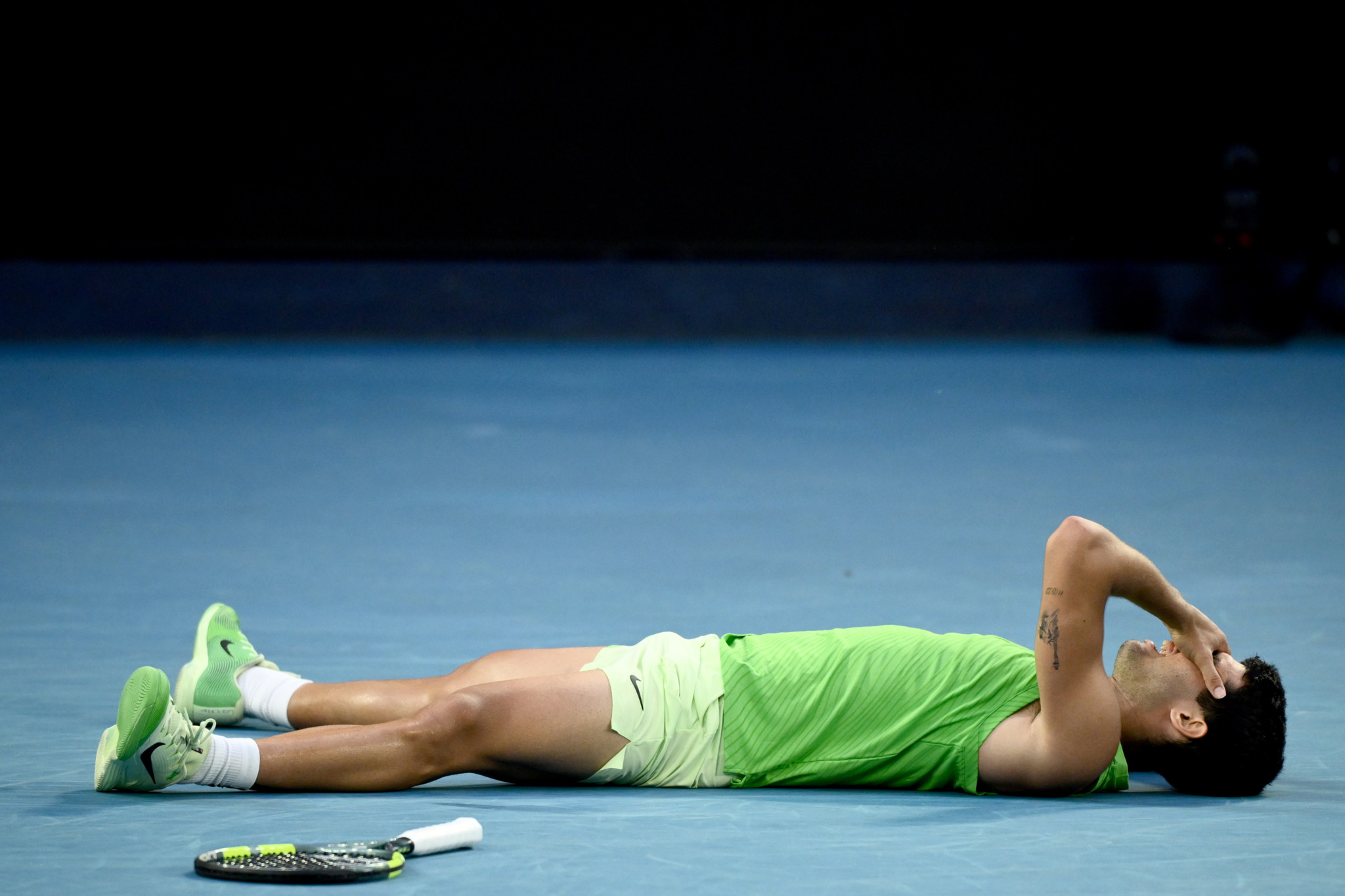 Carlos Alcaraz allongé sur le court après avoir remporté le point décisif en demi-finale contre Alexander Zverev à l’Open d’Australie 2026.
