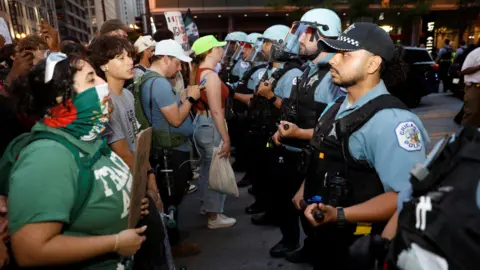 Reuters A row of protestors faces a row of police in riot gear in Chicago on 10 June 2025