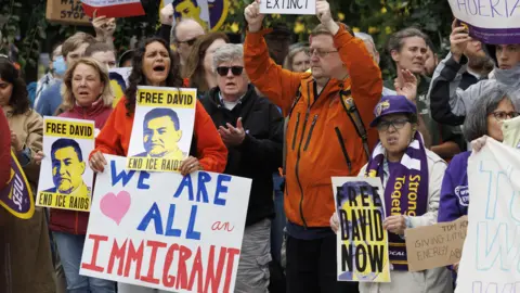 EPA A crowd at a rally hold signs saying "free David, end ICE raids" and "we are all immigrants"