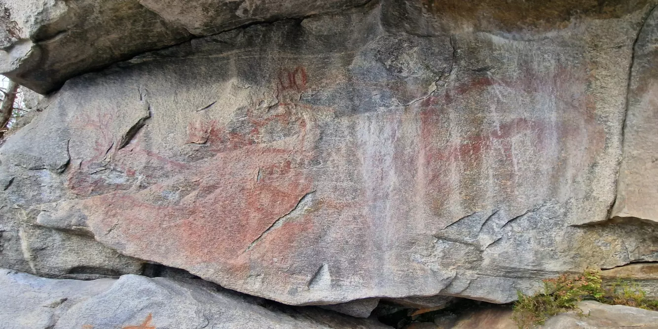 FØR: På denne bergveggen - trygg for vær og vind under et overheng - kan man skimte rødfarge. Men for et utrent øye er det ikke lett å se hva som faktisk er avbildet. Foto: Jan Magne Gjerde/NIKU