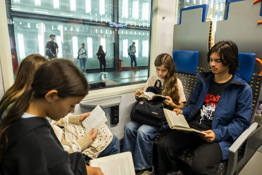 Francisca, gauche, Manon, centre, et Joel, droite, lisent des livres avec d'autres eleves dans un wagon du train Leman Express, lors du voyage Wagons-lit, Lectures en silence, organise par Les Li ...