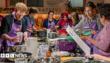 Mel Fu, Jenny Luk and Vicky Yung (L-R) are standing next to each other at a food stall. They are all smiling, with the two women on the right wearing striped aprons.