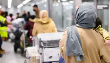 Afghan refugees with luggage wait at an airport terminal as Germany transfers individuals from Pakistan to Berlin under the admission program. (Photo Credit: Jule Hegerscultez/dpa/picture alliance)