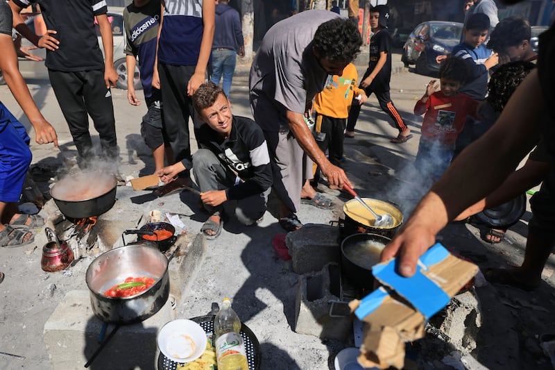 Palestinians prepare food in front of the Unwra school at the Nuseirat refugee camp in Gaza Strip. Photograph: Mahmud Hams/Getty