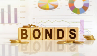Bonds the word on wooden cubes, cubes stand on a reflective surface, in the background is a business diagram. Business and finance concept
