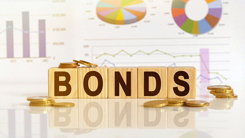 Bonds the word on wooden cubes, cubes stand on a reflective surface, in the background is a business diagram. Business and finance concept