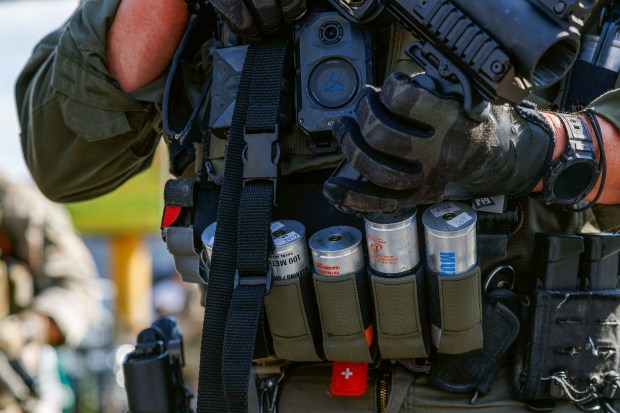 A federal agent holds a launcher and its gas canisters while people protest an immigration sweep near the 3900 block of South Kedzie Avenue in Chicago on Oct. 4, 2025. (Armando L. Sanchez/Chicago Tribune)