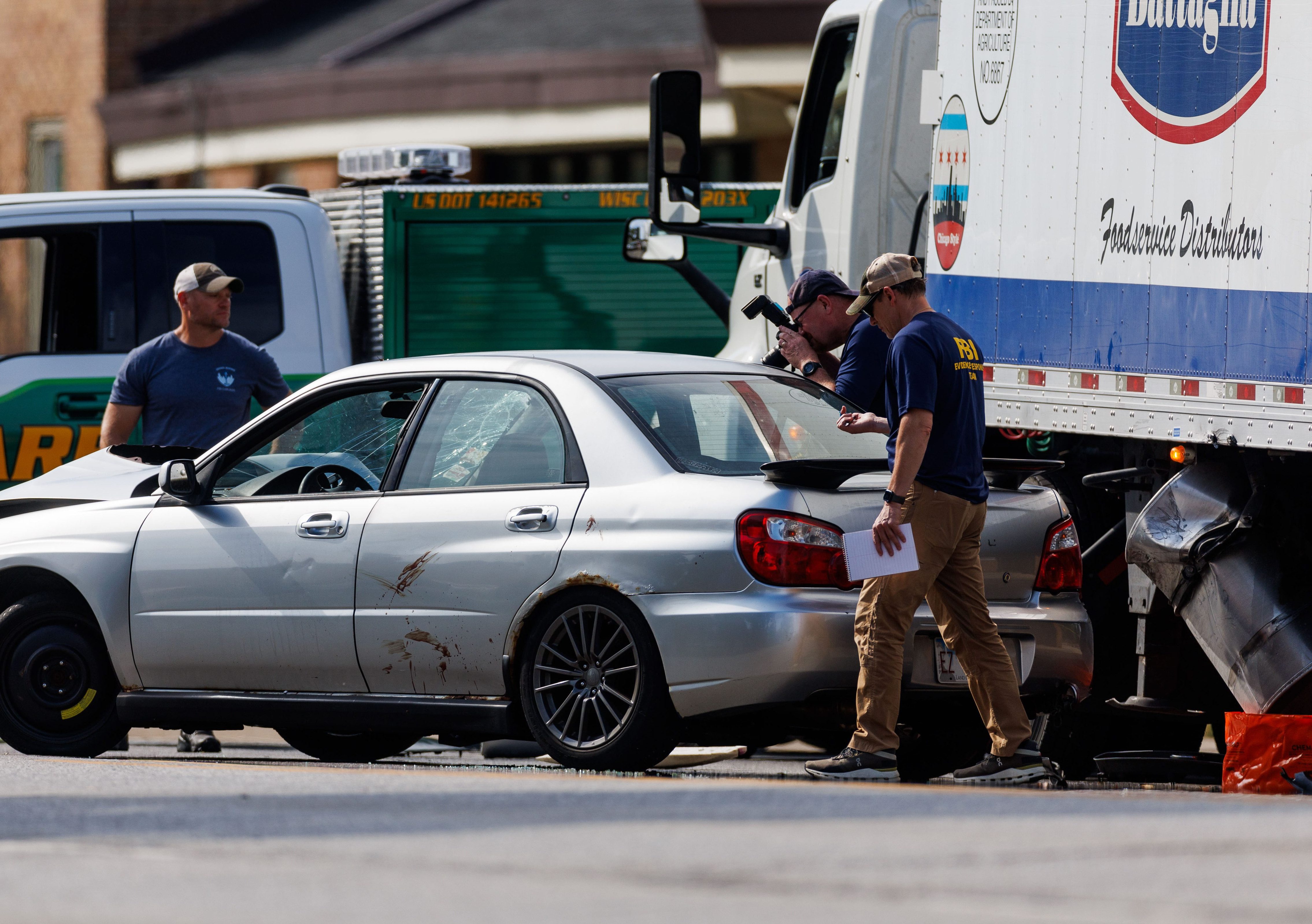 FBI employees watch as a vehicle is towed from the...