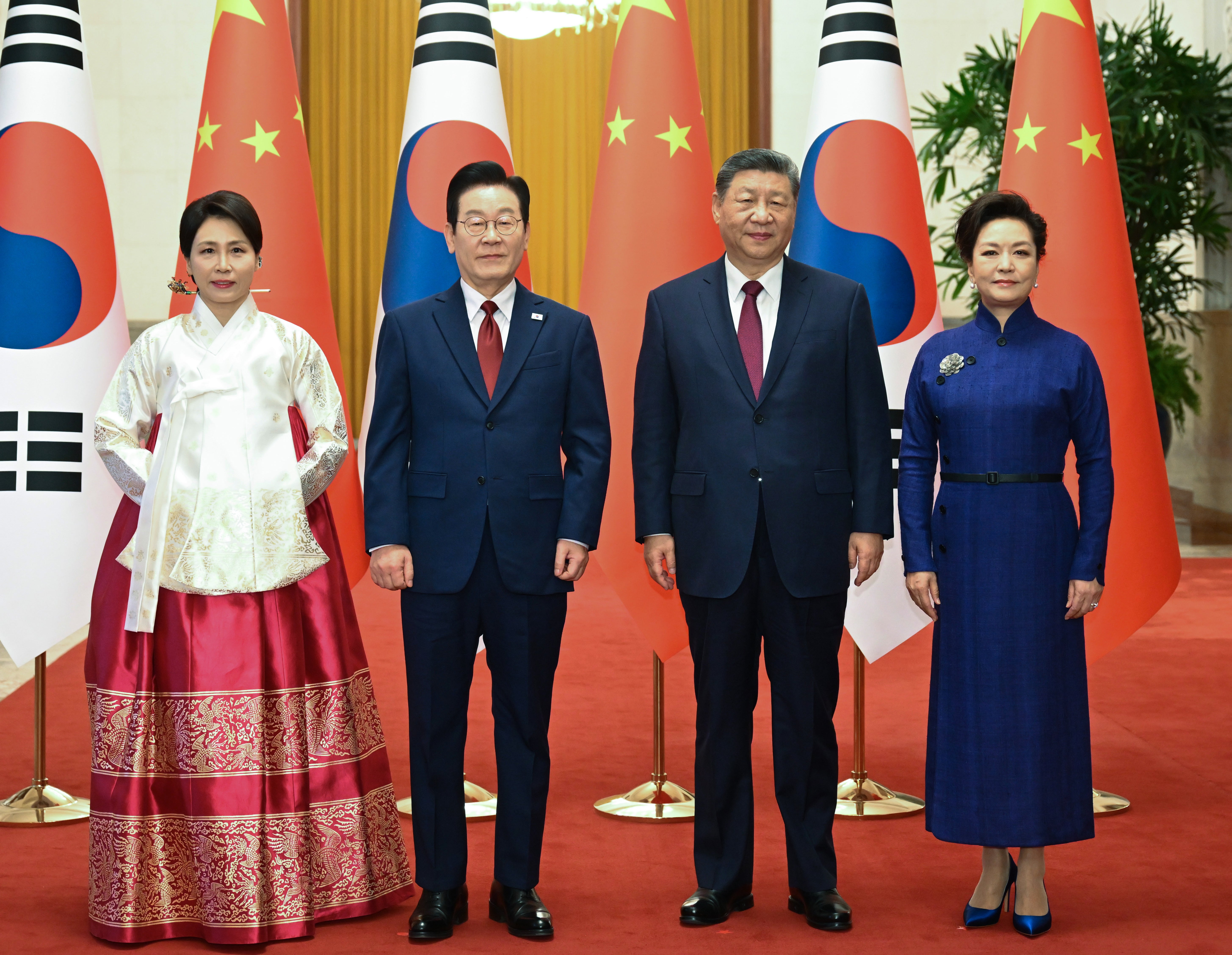 South Korean President Lee Jae Myung, center left, and his wife Kim Hea Kyung, left, stand with Chinese President Xi Jinping, center right, and his wife Peng Liyuan, right, as they pose for a photo shoot at the Great Hall of the People, in Beijing