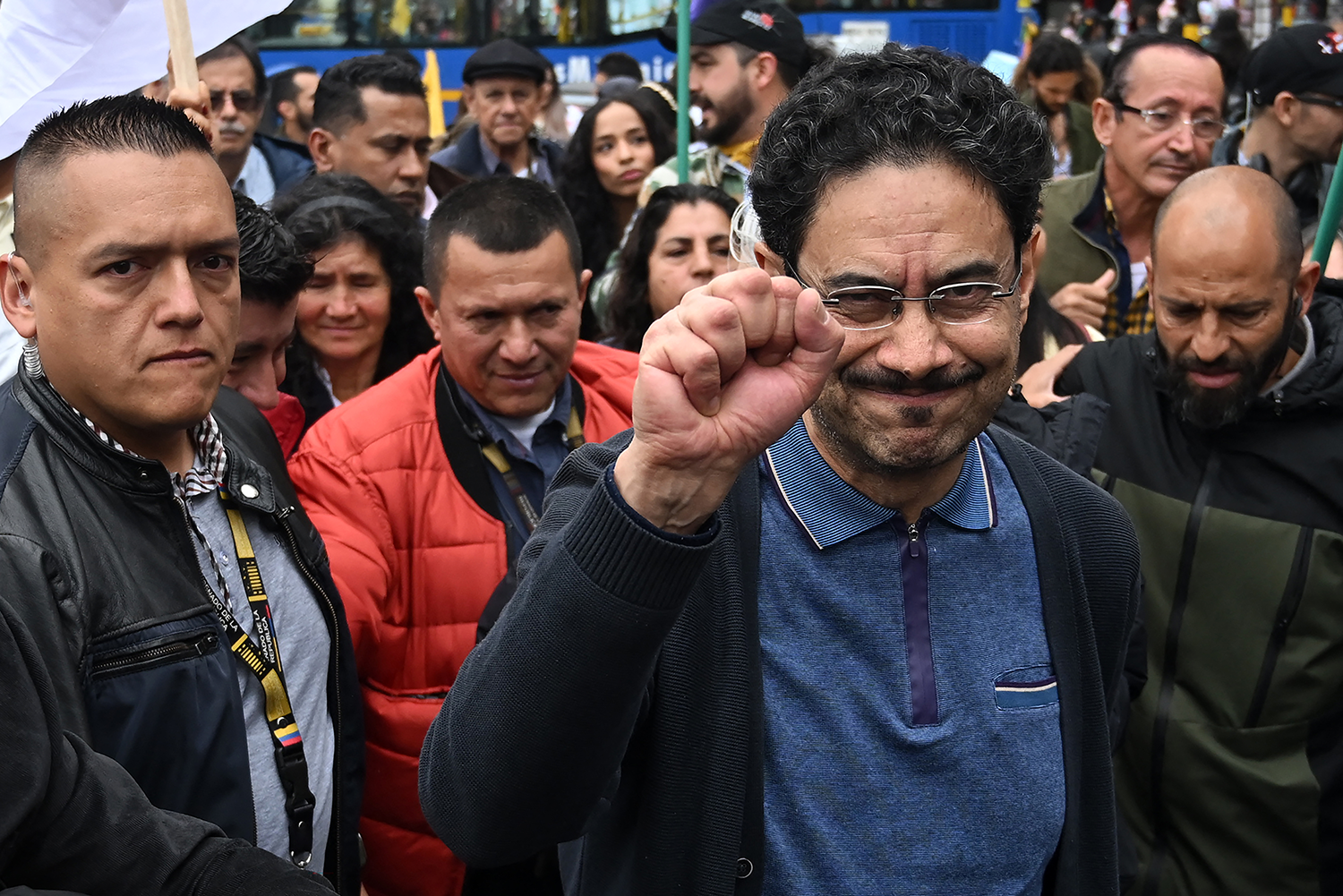 Ivan Cepeda raises his fist while surrounded by a crowd of people and security personnel.