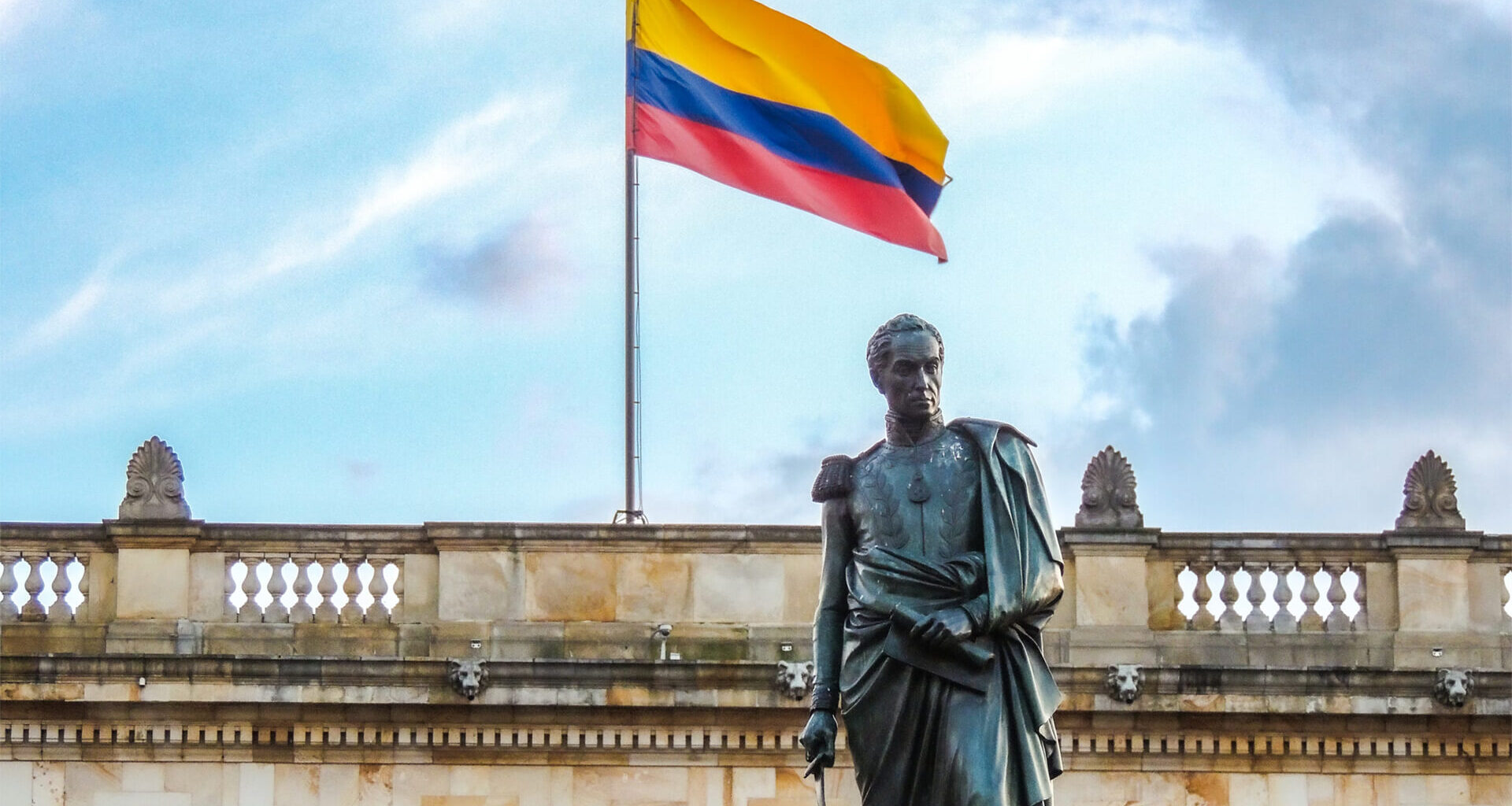 the statue of Simón Bolívar standing before Colombia’s National Capitol, with the flag waving