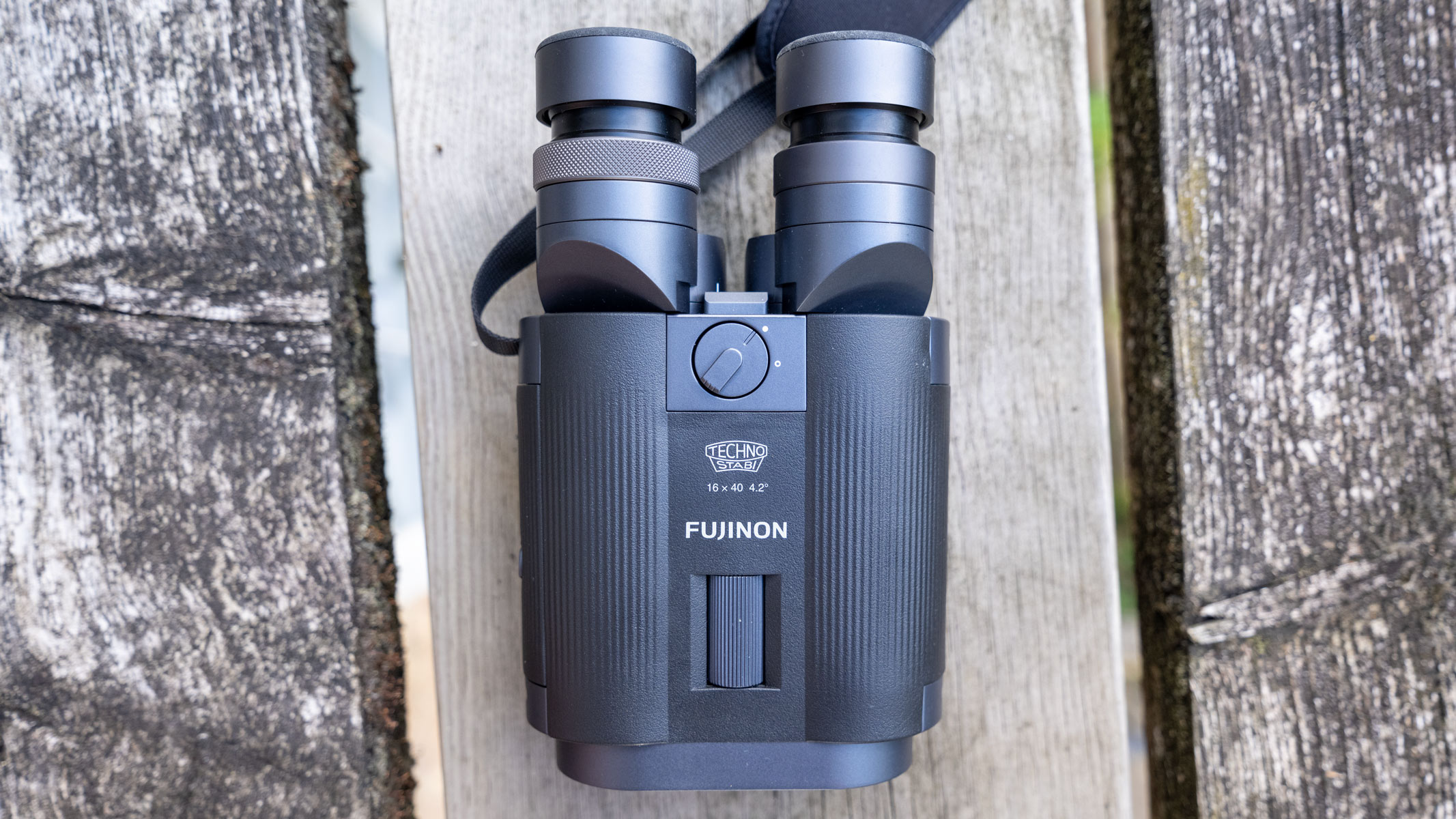 A birds-eye view of the Fujifilm Techno-Stabi TS-L 1640 image-stabilized binoculars on some wooden planks.
