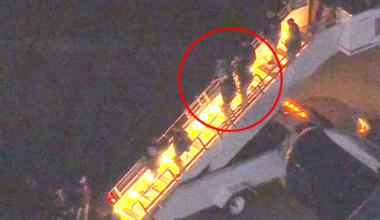 Et fly har nettopp landet, og flere personer er i ferd med å gå ned en trapp fra flyet. Svart bakgrunn indikerer at det er mørkt, mens trappen er belyst. Ingen ansikter er tydelige i bildet. Handlingen skjer i en flyplasssetting, med pressen til stede. (Bildebeskrivelsen er laget av en KI-tjeneste)