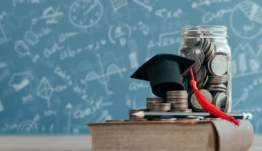 An old book with a college cap, coins and a money jar atop it, in front of a chalk-covered board.