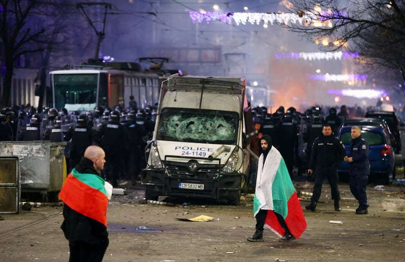 Police stand in formation as protesters in Bulgarian flags walk past during a rally against austerity measures in Sofia on December 1 (Valentina Petrova/AP)