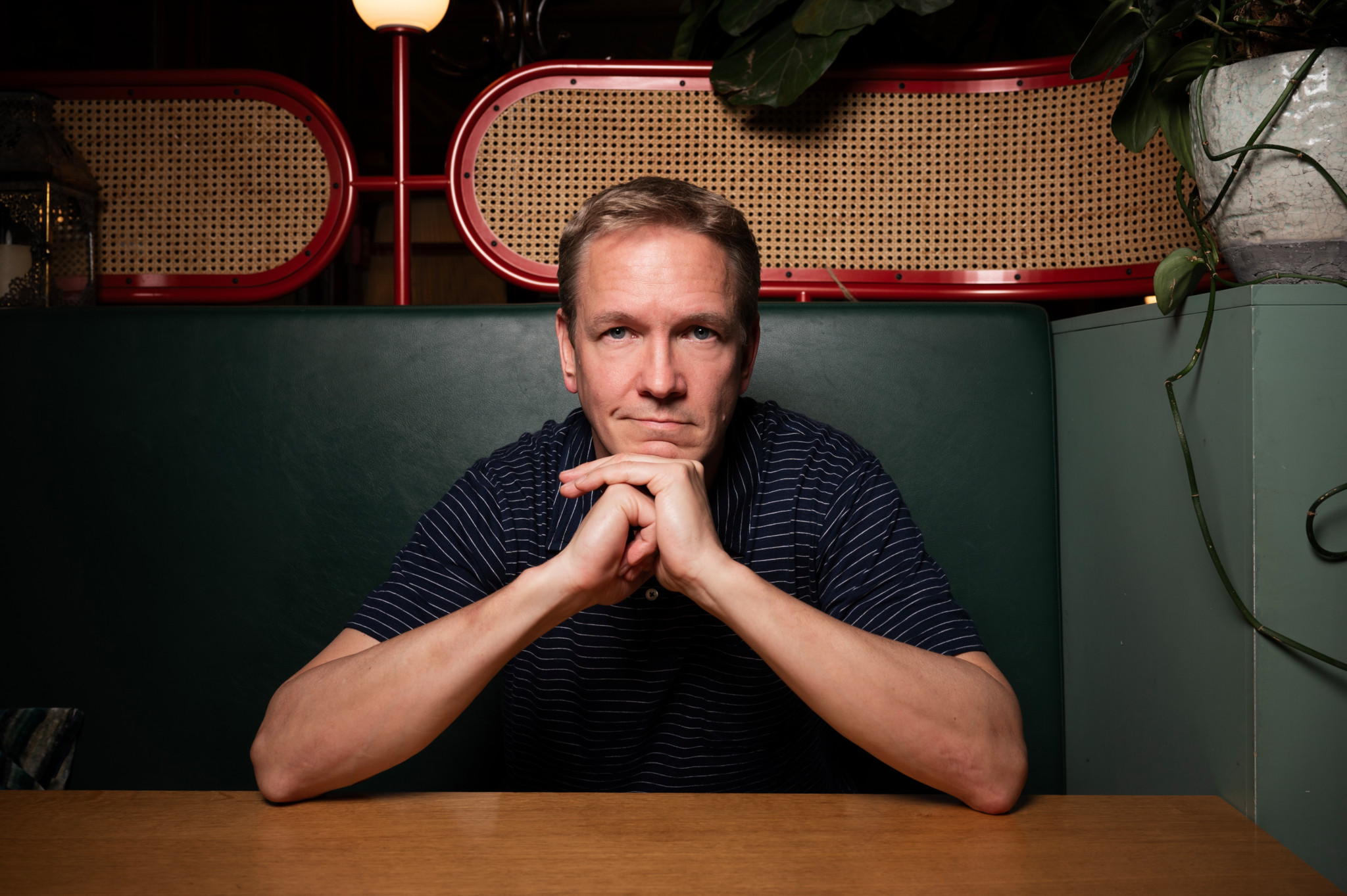 Vincent Kucholl sitzt an einem Tisch in einem Restaurant in Lausanne, den Kopf auf die Hände gestützt, im Juni 2025.