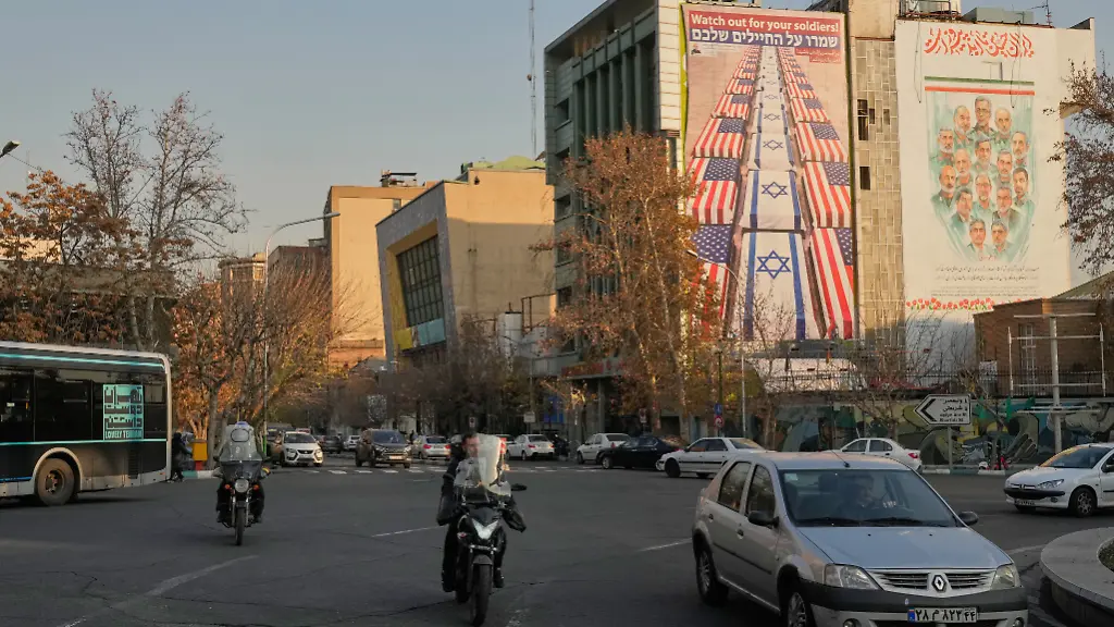 Fahrzeuge-fahren-vorbei-an-Bannern-mit-einem-Anti-US-und-Anti-Israel-Bild-l-und-Portraets-der-iranischen-Kommandeure-und-Atomwissenschaftler-die-bei-israelischen-Angriffen-im-Juni-2025-getoetet-wurden-auf-dem-Felestin-Palaestina-Platz-in-der-Innenstadt-von-Teheran