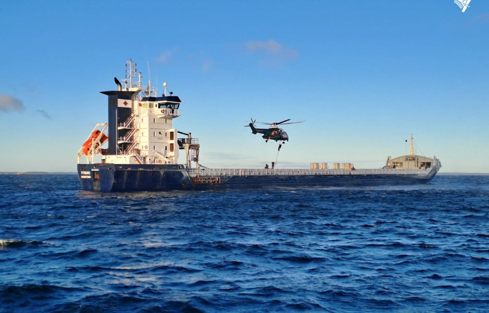 Finnish authorities repel from a helicopter onto the deck of the M/V Fitburg