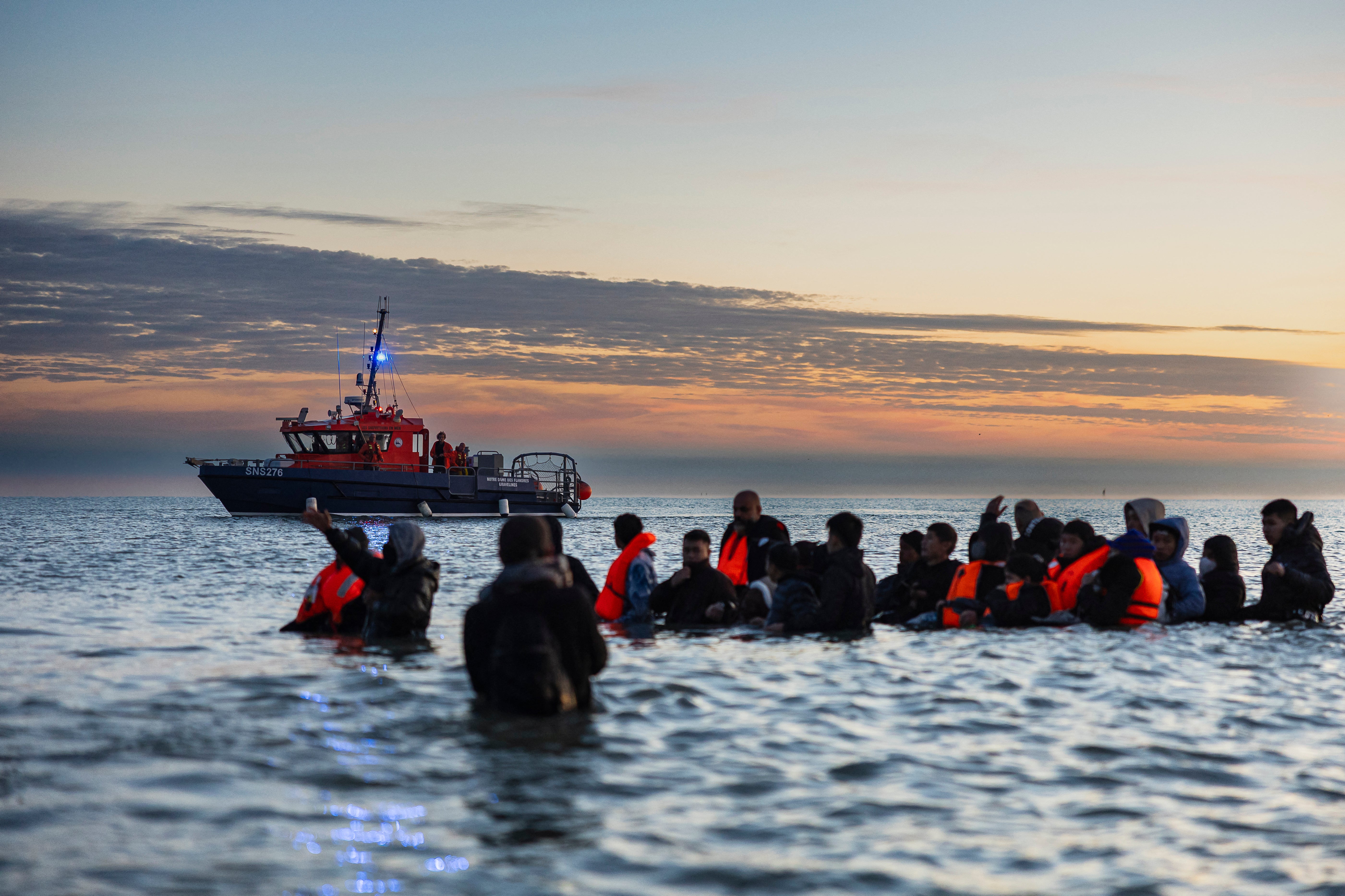 A French rescue boat sails near migrants waiting to board a smuggler's boat in an attempt to cross the English Channel off the beach of Gravelines, northern France