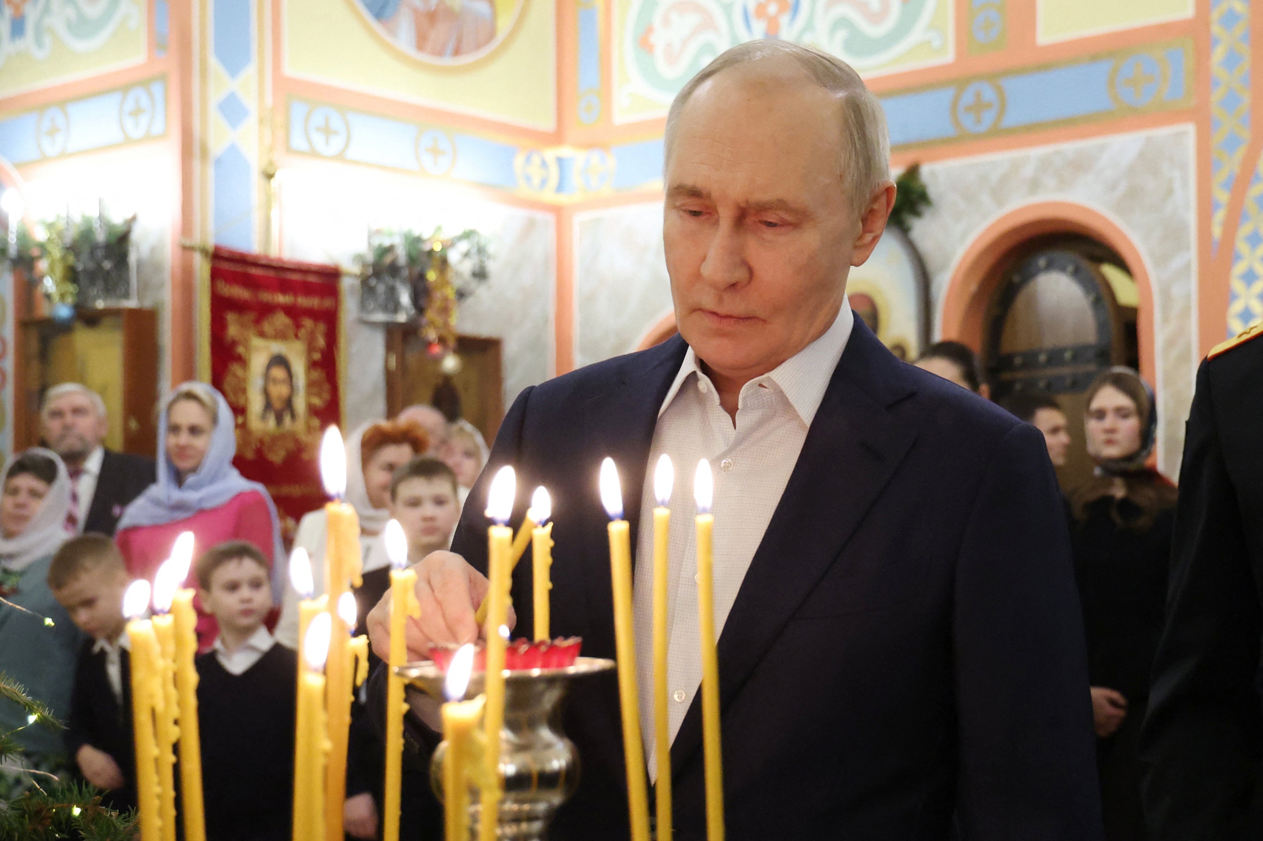 Russia's president Vladimir Putin lights a candle as he attends a Christmas service at a church in the Moscow region