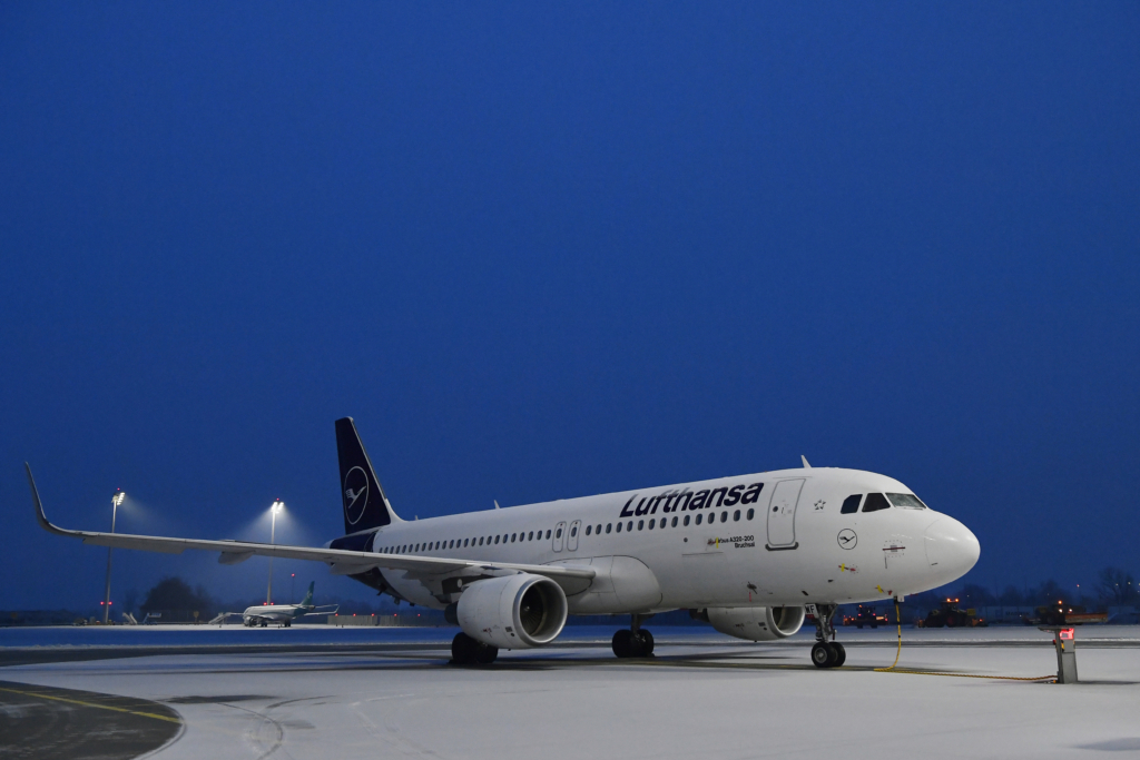 A Lufthansa aircraft on a dark evening surrounded by snow