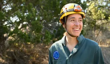 A woman wearing a yellow helmet and blue sweater smiles