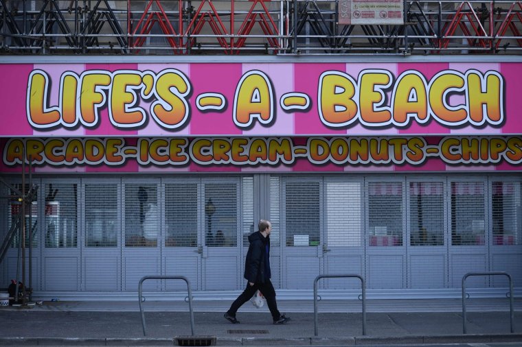 A man passes a closed establishment on the seafront in Margate south east England, on May 16, 2020, following an easing of lockdown rules in England during the novel coronavirus COVID-19 pandemic. - Don't come to Margate!" In this southern English seaside resort, that's the message a group of shopkeepers terrified of a second wave of coronavirus are trying to get across, while others are in a hurry to reopen in order to survive. (Photo by BEN STANSALL / AFP) / TO GO WITH AFP STORY BY VERONIQUE DUPONT (Photo by BEN STANSALL/AFP via Getty Images)