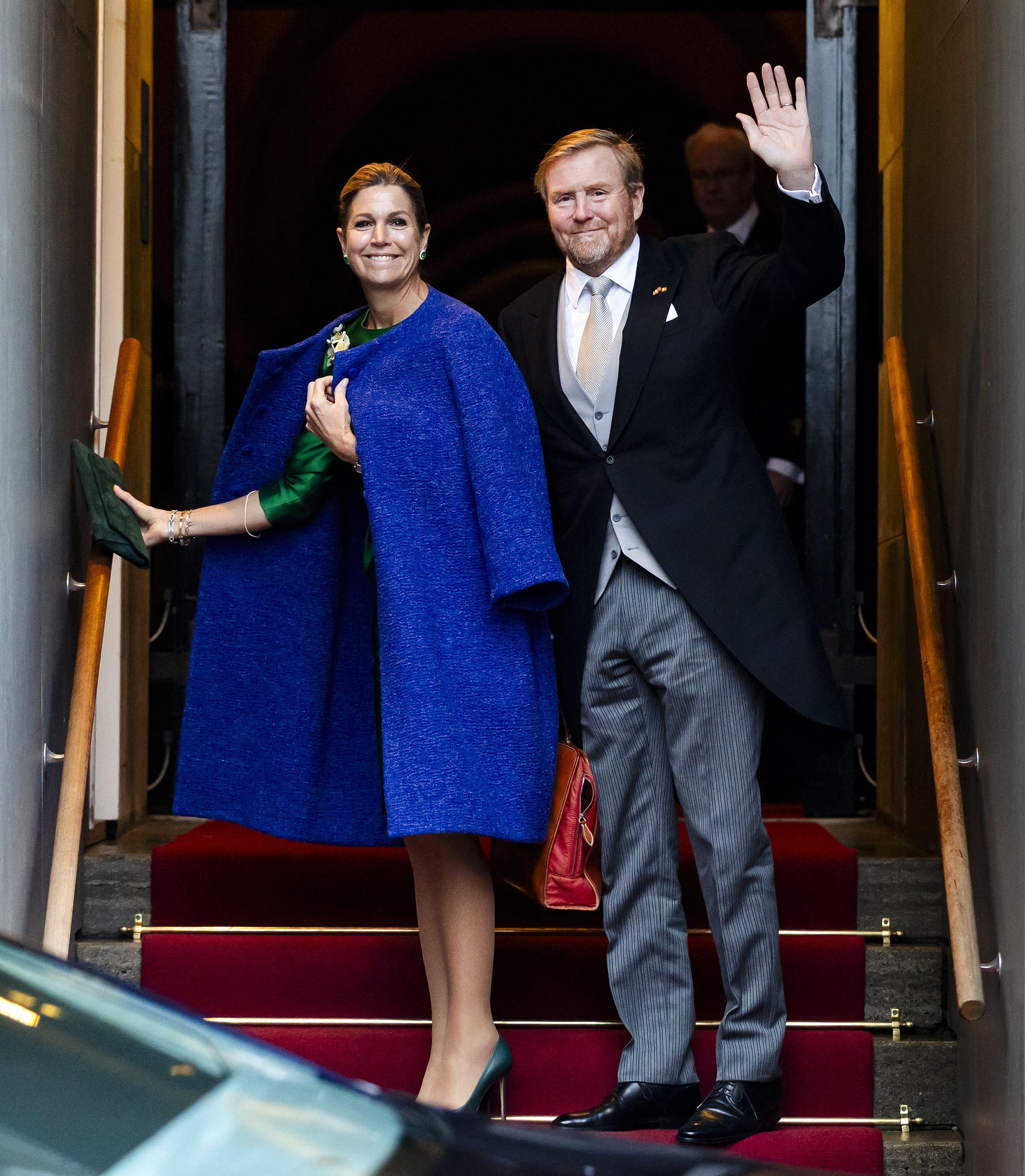 Queen Maxima wearing a blue coat standing on stairs next to King Willem-Alexander