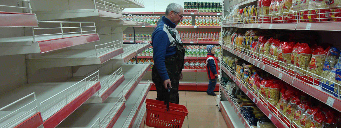 A man shopping in a supermarket in Moscow, with some shelves empty.