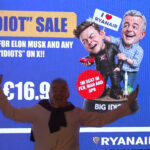 Ryanair CEO Michael O'Leary posing in front of the Big "Idiot" Sale banner before his press conference.