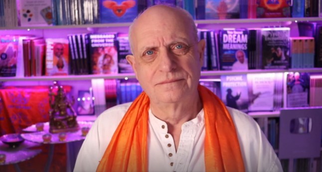Craig Hamilton-Parker wearing a white shirt and orange scarf in one of his YouTube videos