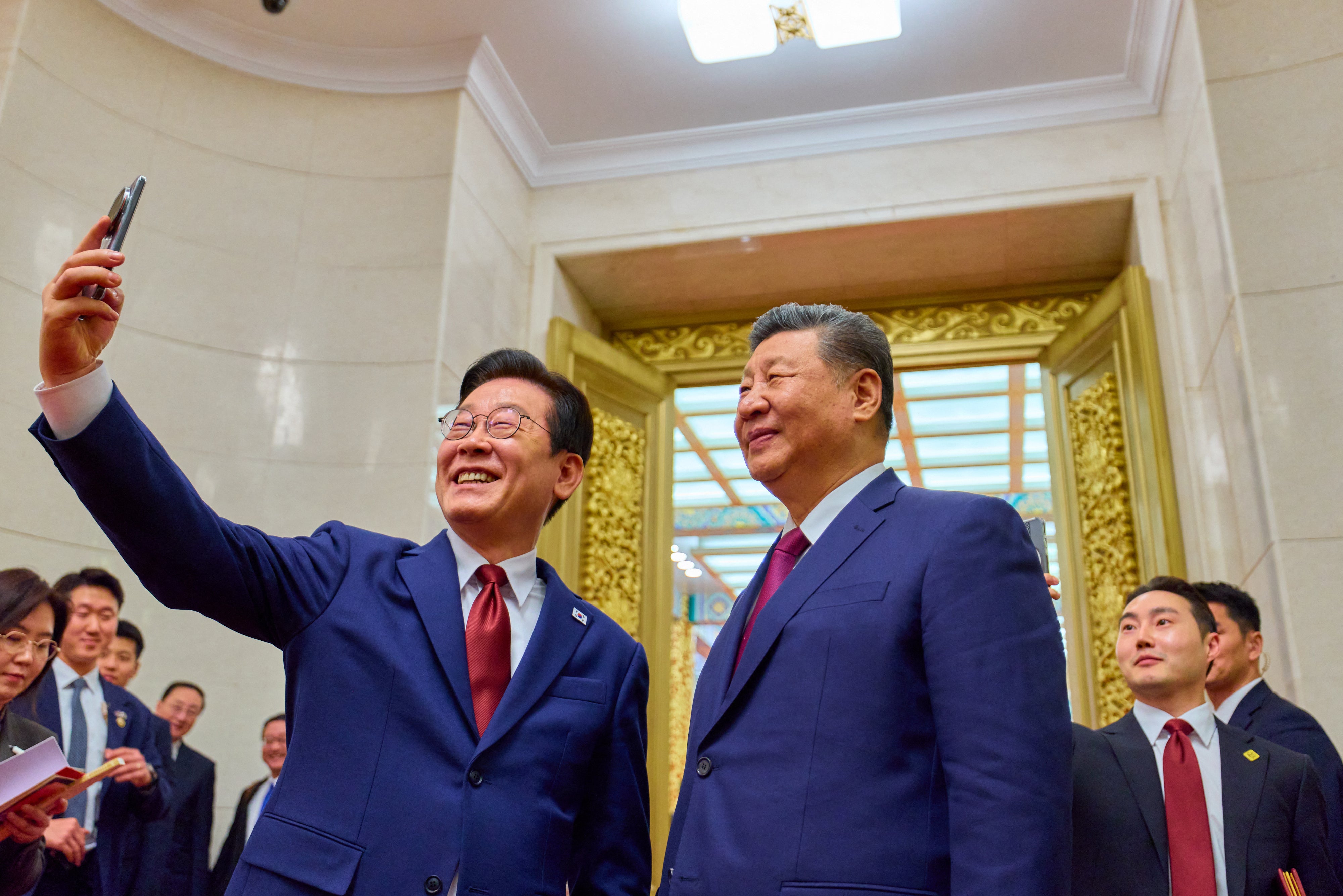 South Korea's President Lee Jae Myung (L) takes a selfie with China's President Xi Jinping (R) after a dinner at the Great Hall of the People in Beijing