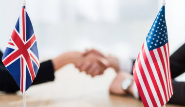 US and UK flags with a selective focus on diplomats shaking hands. Licensed by Envato Elements