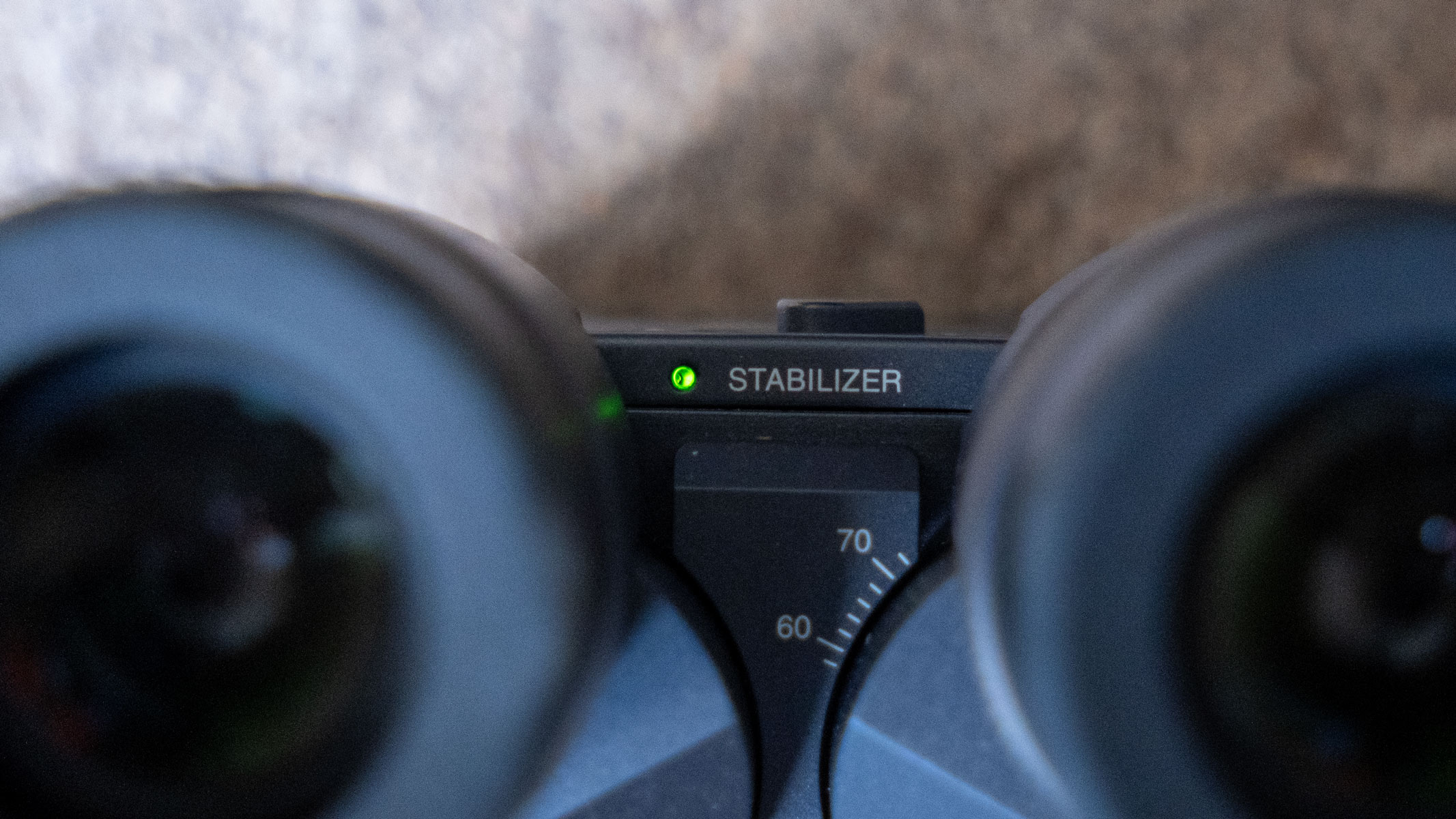 A close-up of the green image-stabilizer light with inter-pupillary distance markings on the Fujifilm Techno-Stabi TS-L 1640 image-stabilized binoculars.