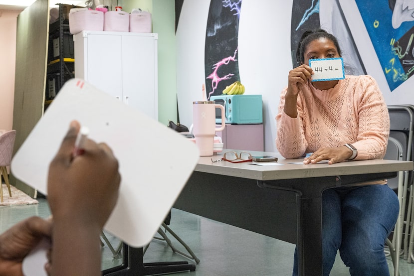 Saki Milton, Gems Camp founder and director, holds up division equation flashcards while...